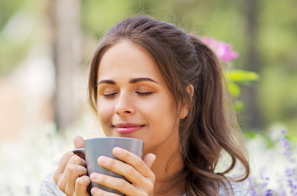 Woman drinking tea in garden. Learn more how home water filtration systems may improve the taste of your tea and coffee.